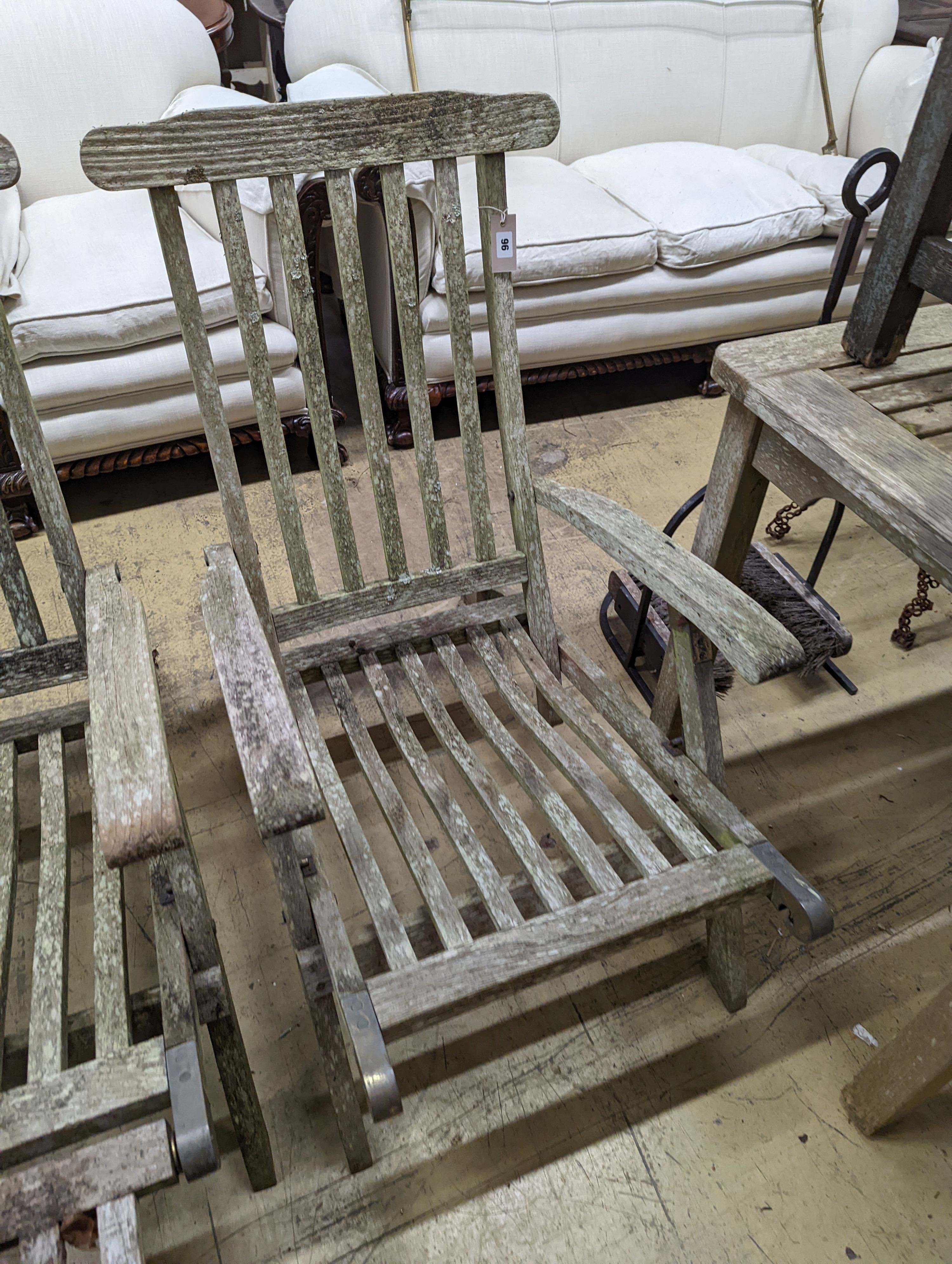 A pair of weathered teak garden steamer chairs, one lacks foot piece. H-93cm.
